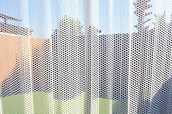 perforated plastic sheet, wonder, undulating, photorealistic, in a suburban backyard, highly detailed, with openings casting shadows, 8K resolution, frosted white, afternoon sun, shot with a 24mm lens
