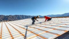 construction plastics in use, focused, workers installing plastic roofing, photorealistic, sunny construction site with mountains in the background, highly detailed, people in action and materials being secured, broad color palette, natural afternoon light, shot with a 35mm lens.